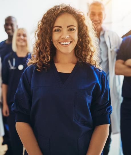 Female nurse standing in front of smiling colleagues