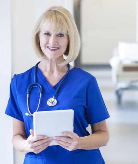 Older nurse standing with tablet